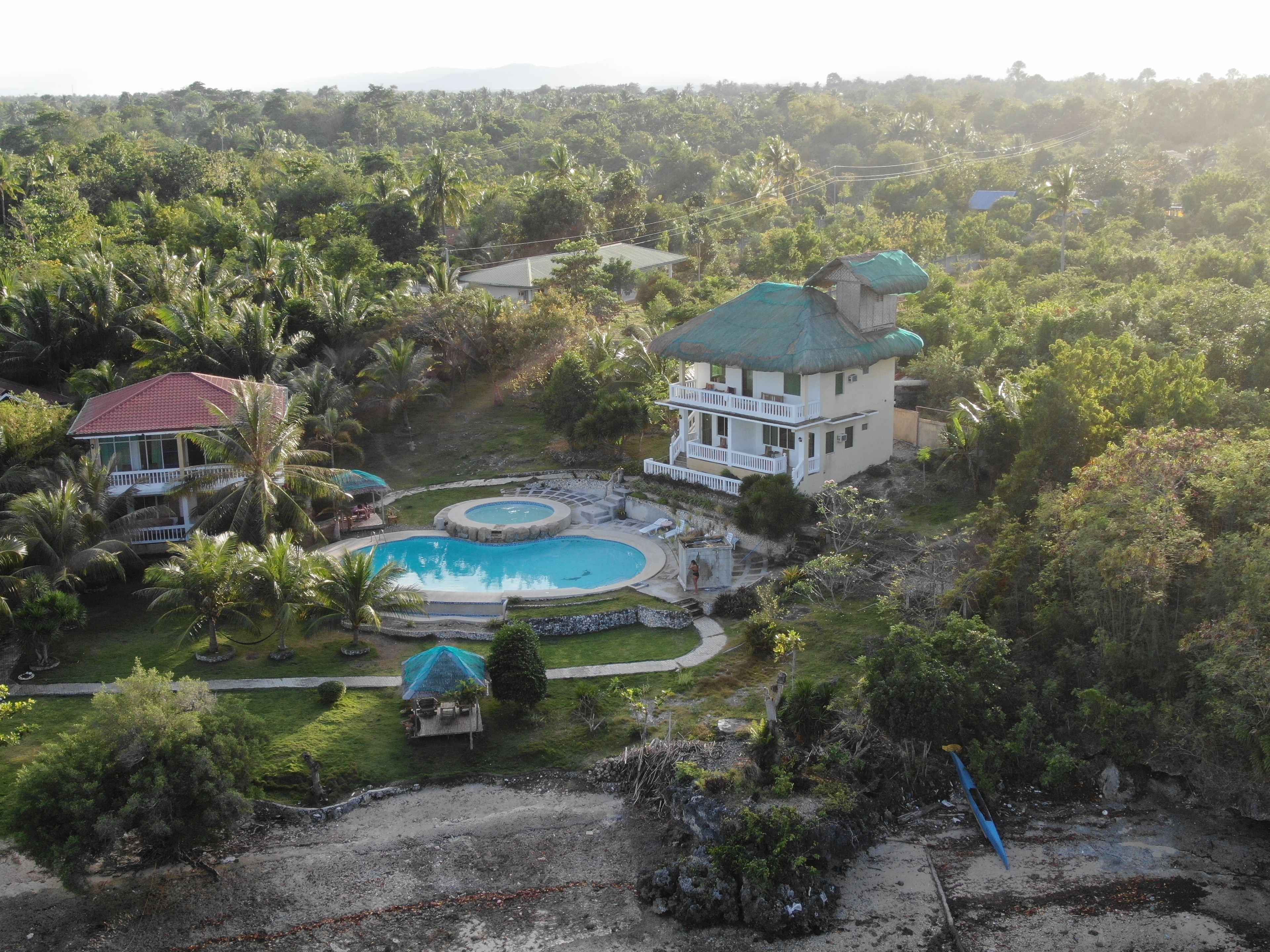 A large house with a swimming pool surrounded by lush greenery.