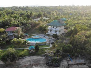 A large house with a swimming pool surrounded by lush greenery. - Moalboal Beach Resort (Moalboal)