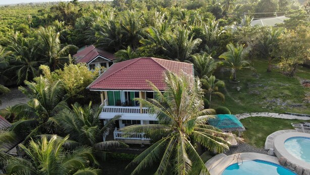 A house surrounded by lush greenery, a swimming pool, and a tennis court. - Moalboal Beach Resort (Moalboal)