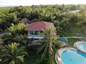 A house surrounded by lush greenery, a swimming pool, and a tennis court. - Moalboal Beach Resort (Moalboal)