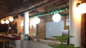 A restaurant interior with a counter, chairs, a plant, and a computer monitor. - Moalboal Beach Resort (Moalboal)