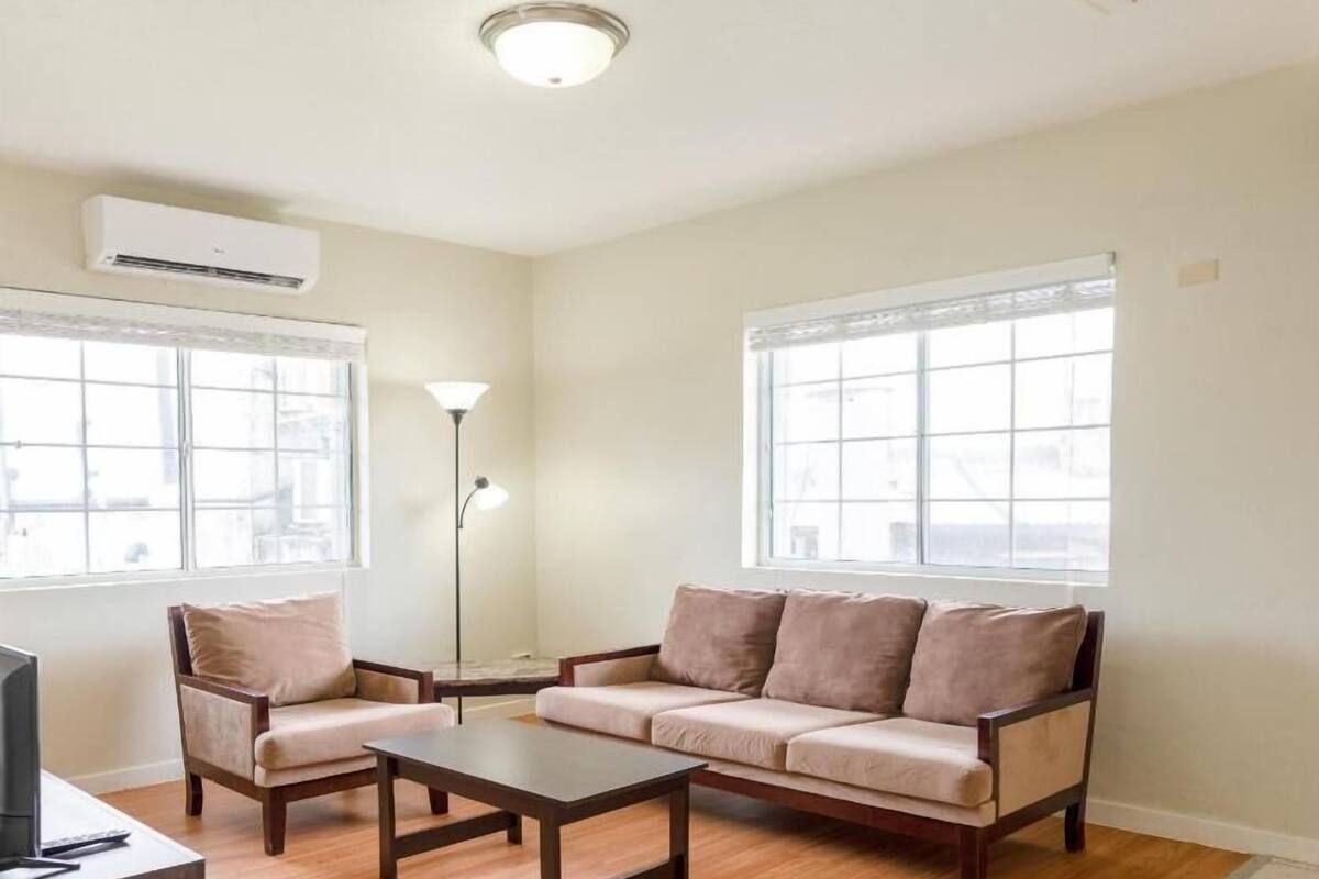 A living room with a sofa, two armchairs, a coffee table, and a TV.