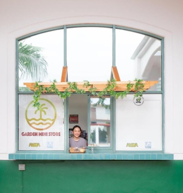 Fachada de una tienda con un letrero que dice "Garden Mini Store" y un logotipo con palmeras.
