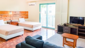 A hotel room with two beds, a TV, a desk, and a balcony. - Garden Villa Hotel (Tamuning)