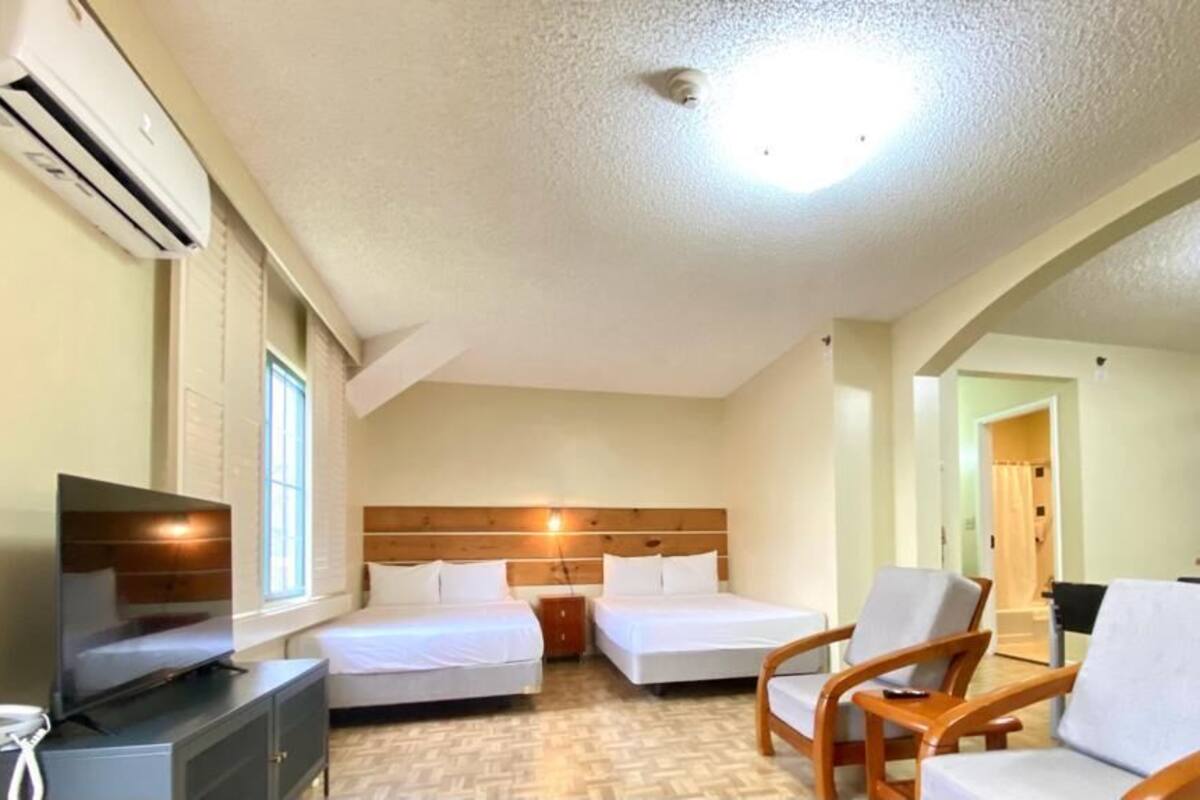 A hotel room with two beds, a TV, a desk, and a chair.
