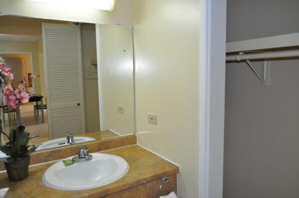 A bathroom with a sink, mirror, and towel rack. - Garden Villa Hotel (Tamuning)
