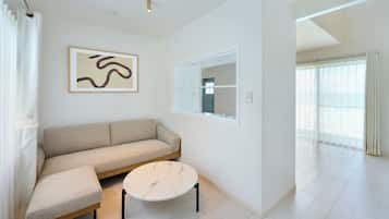 A modern living room with a beige sofa, a round marble coffee table, and a large window with a view.