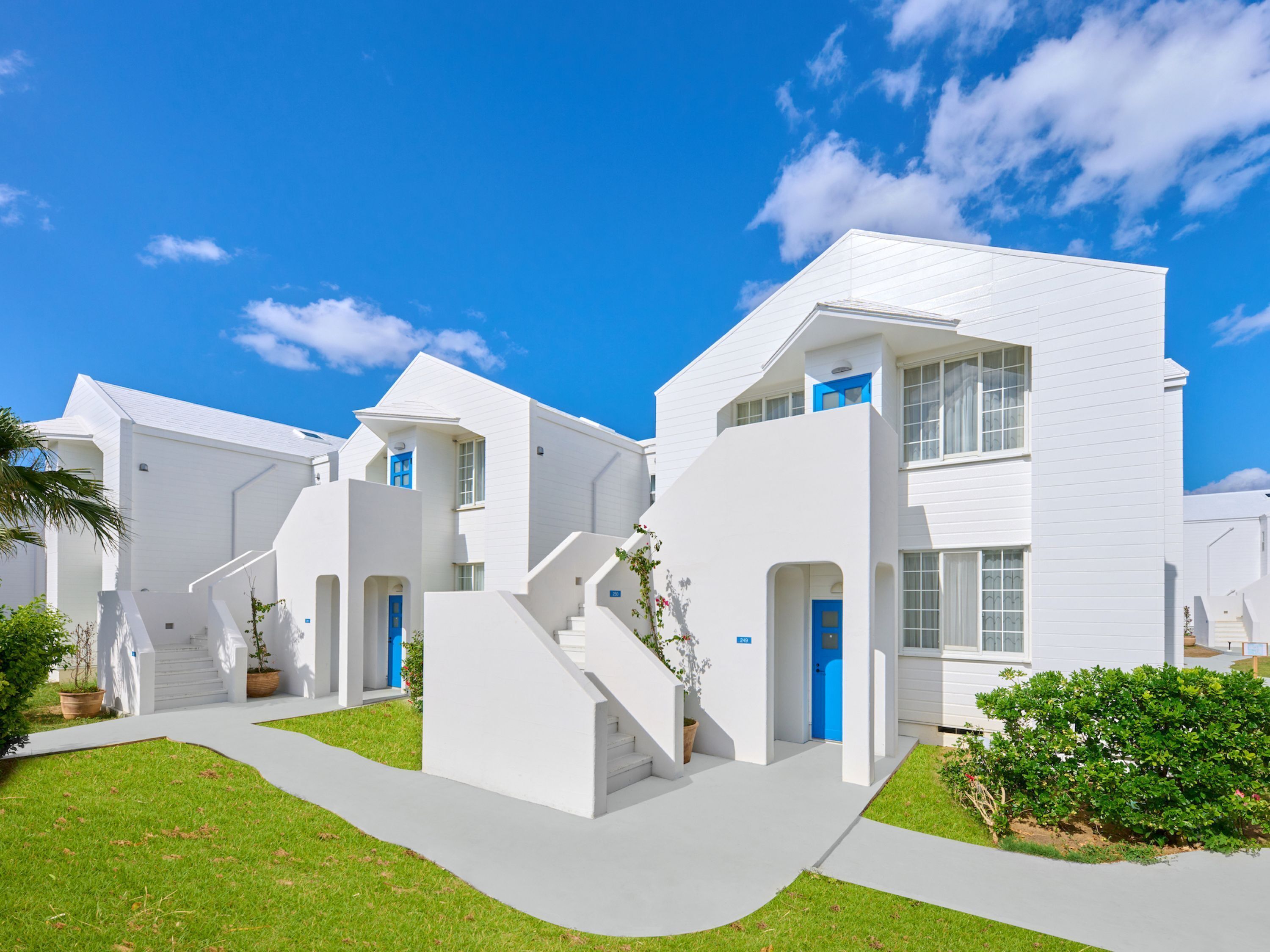 A row of white buildings with blue doors and windows, arranged in a modern architectural style.