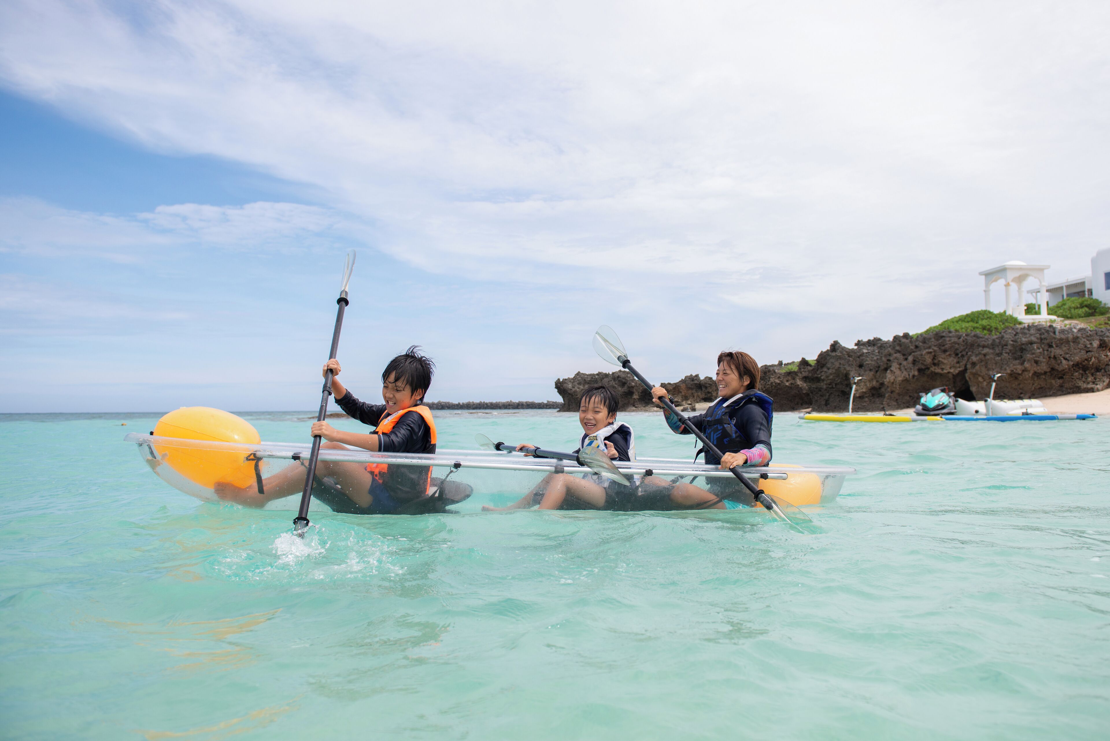 Three people in a kayak on clear turquoise water.
