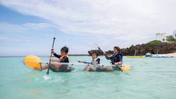 Three people in a kayak on clear turquoise water.