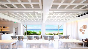 A bright, open-plan room with a view of the beach, white furniture, and a ceiling with a grid pattern. - Pricia Resort Yoron (Yoron)