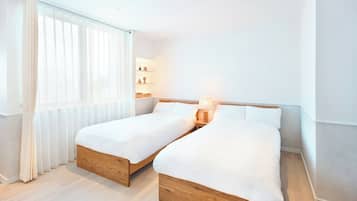 A double bed room with a wooden headboard, a bedside table with a lamp, and a window with sheer curtains.