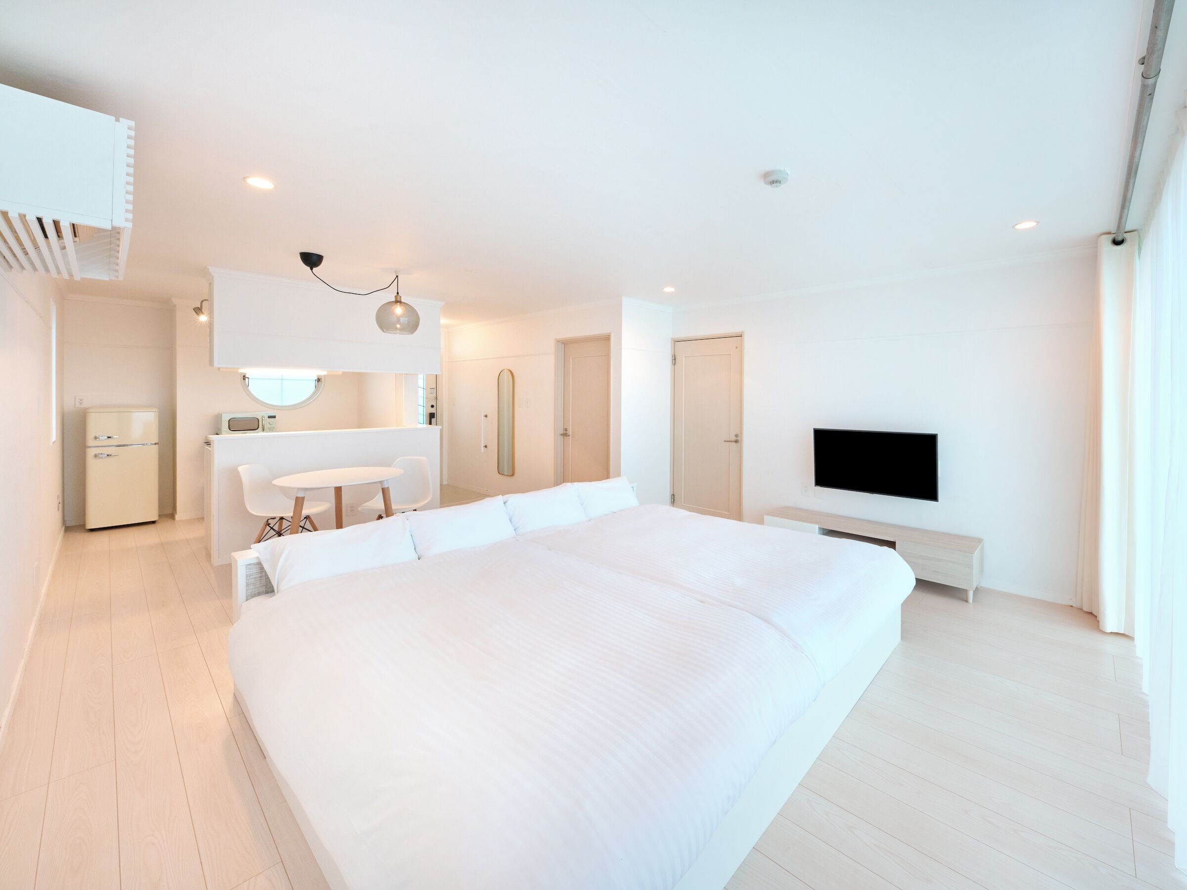 Habitació d'hotel moderna amb un llit gran, un escriptori, televisió i una cuineta.