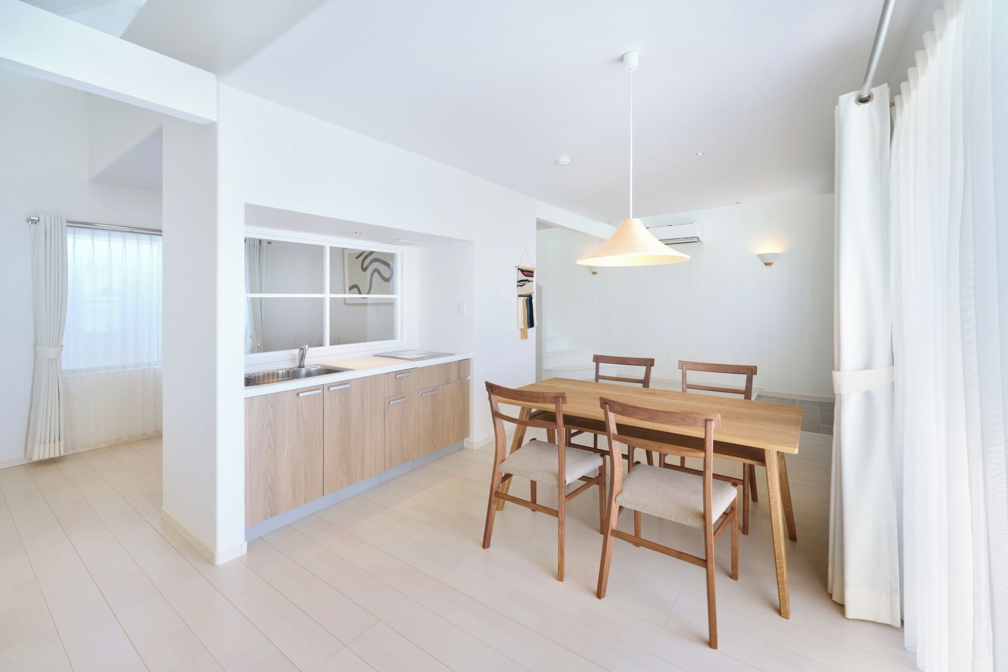 Una cocina moderna con una isla central, armarios de madera y un comedor con mesa y sillas de madera.