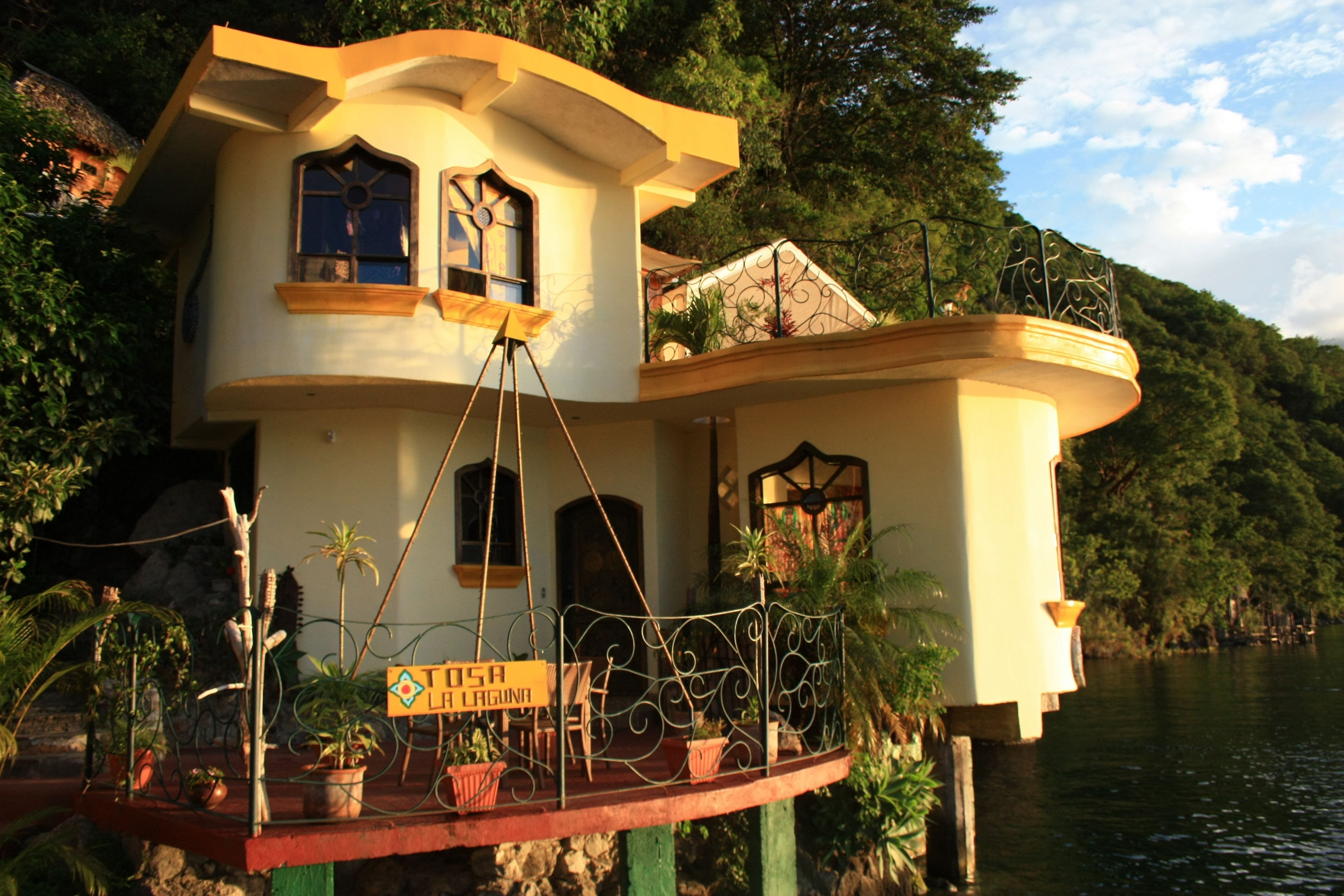 A houseboat with a balcony, surrounded by water and greenery.