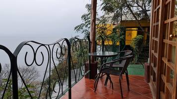 A balcony with a metal railing, a table, and two chairs.