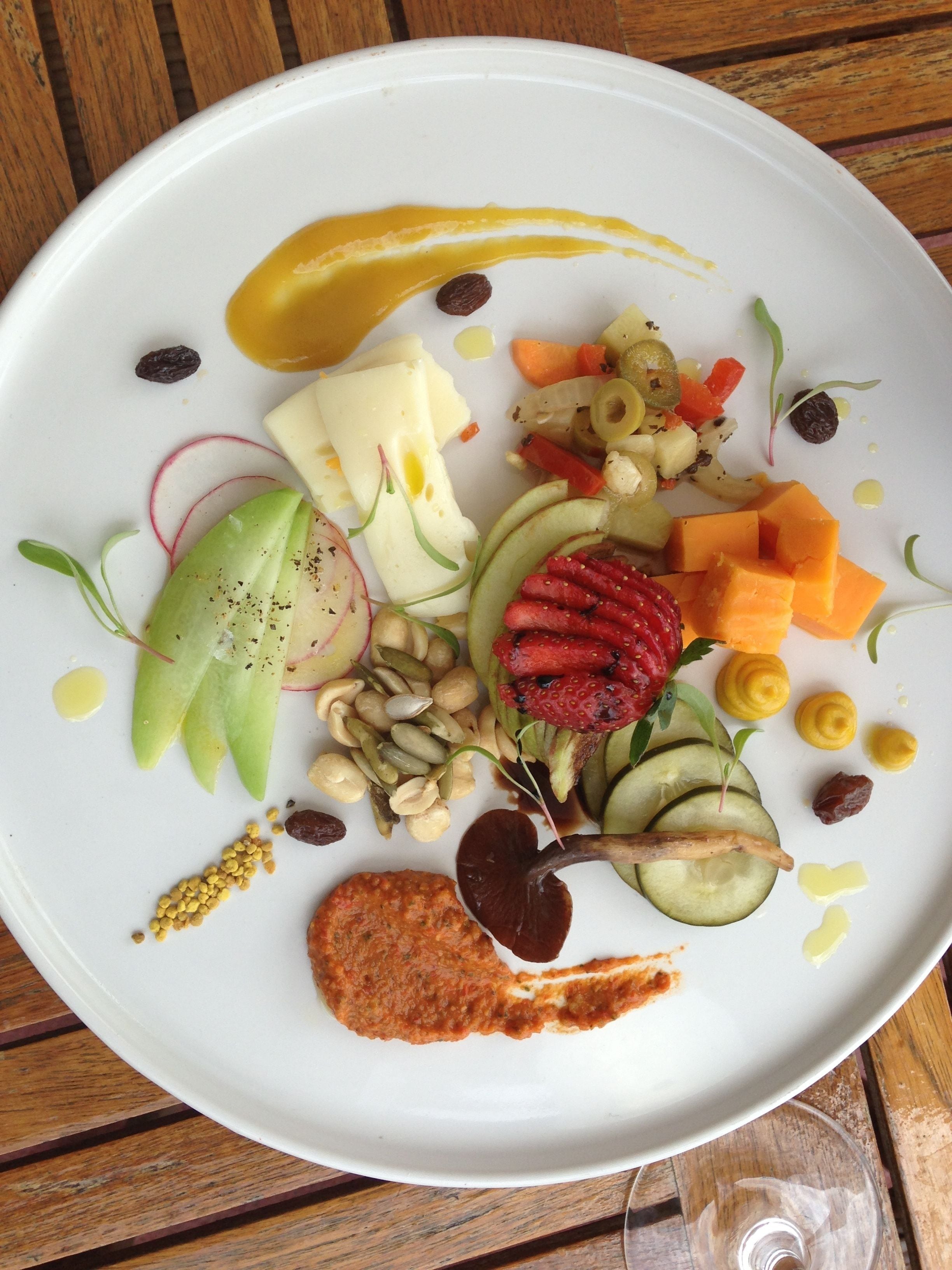 Um prato branco com frutas, legumes e um pouco de molho vermelho.