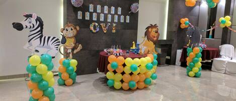 Una habitación decorada con globos de motivos animales, un cartel de cumpleaños y una mesa con adornos para la fiesta.