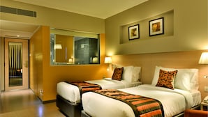 Ein Hotelzimmer mit zwei Betten, einem großen Spiegel und einer Tür zu einem Badezimmer.