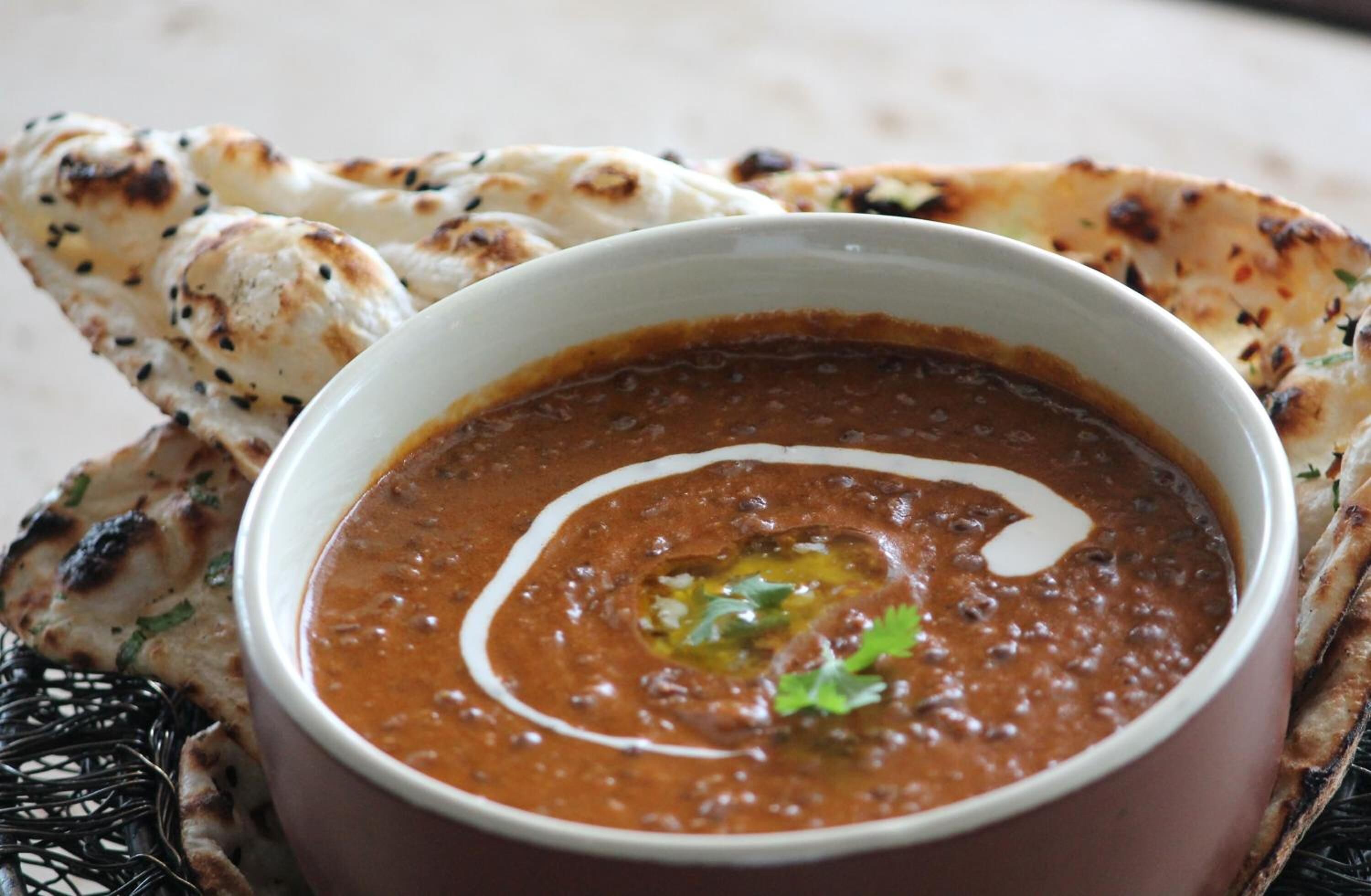 A bowl of curry with naan bread.
