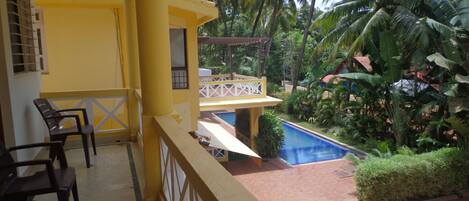Un balcón con piscina, sillas y vistas a palmeras.