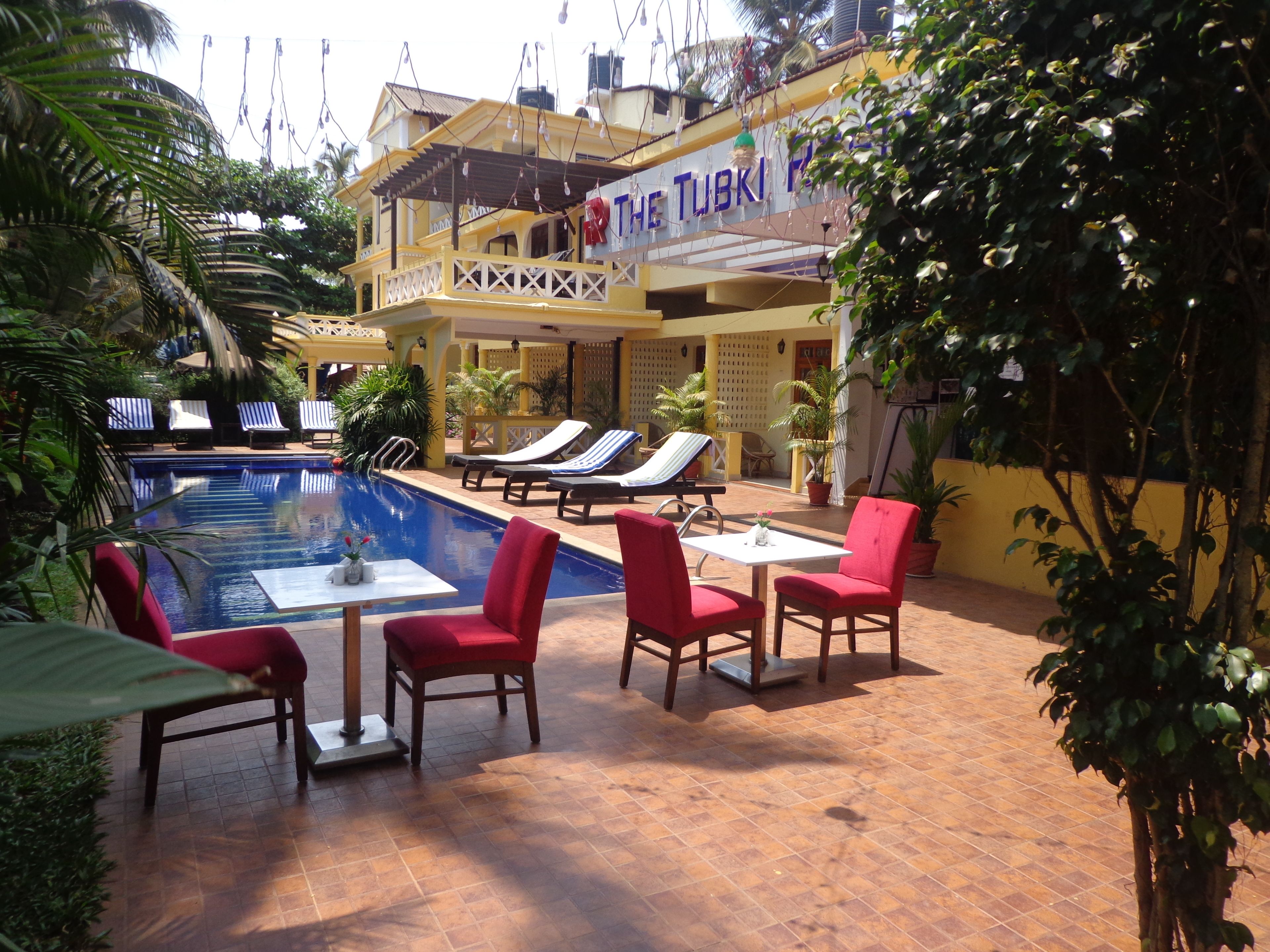 A poolside area with lounge chairs, a table, and a sign reading "The Tubki Place".