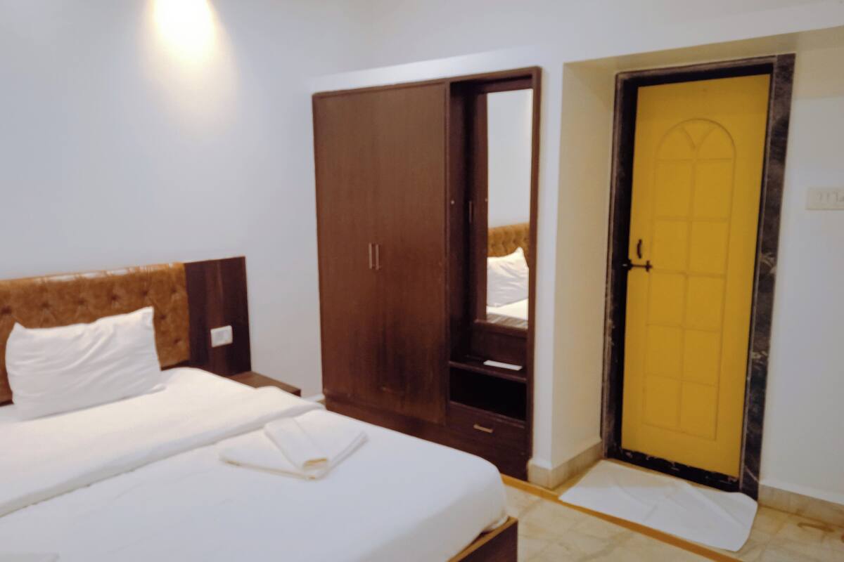 A hotel room with a bed, a wardrobe, and a door.