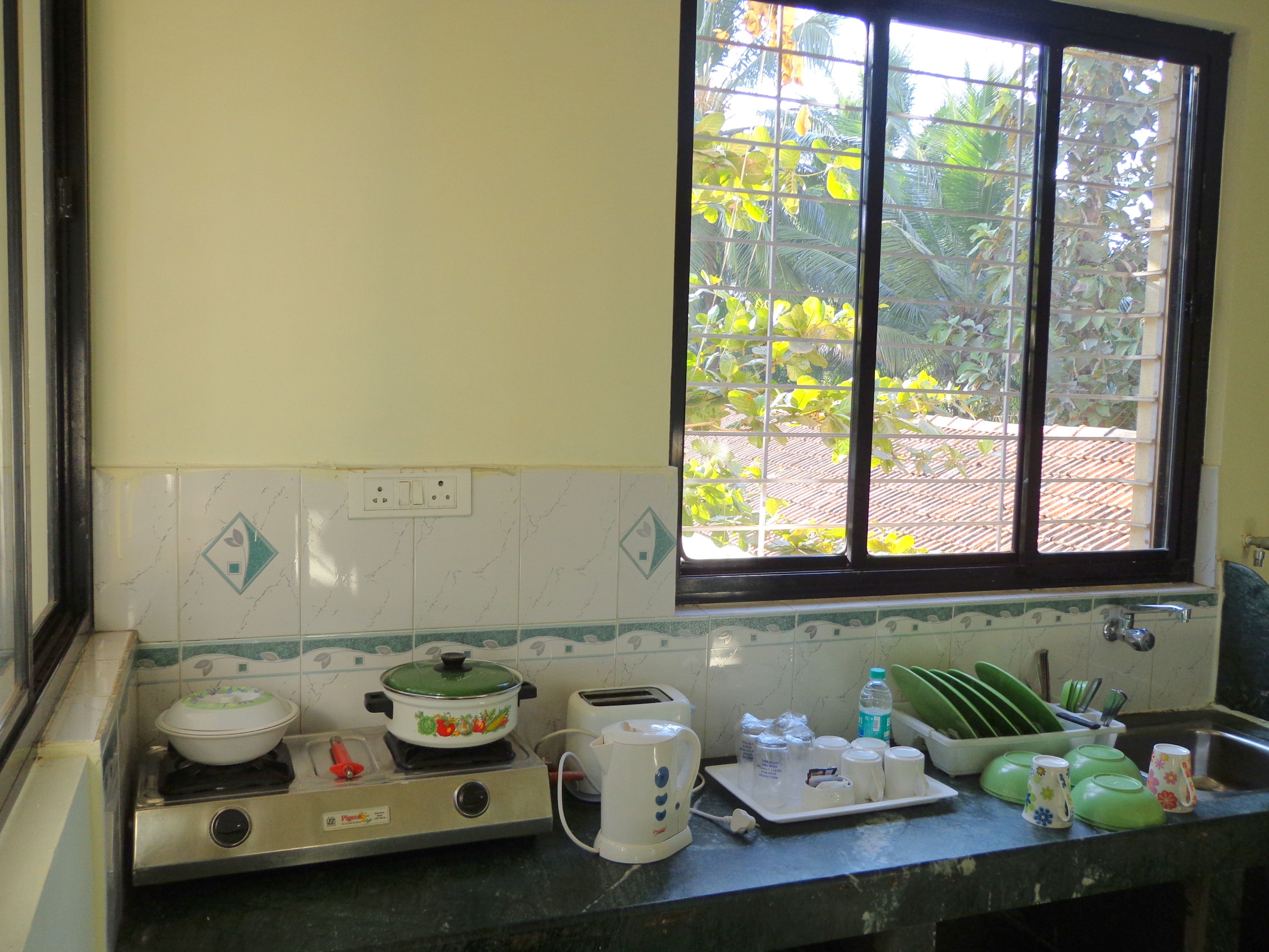 A kitchen with a stove, a window with a view of greenery, and a sink.