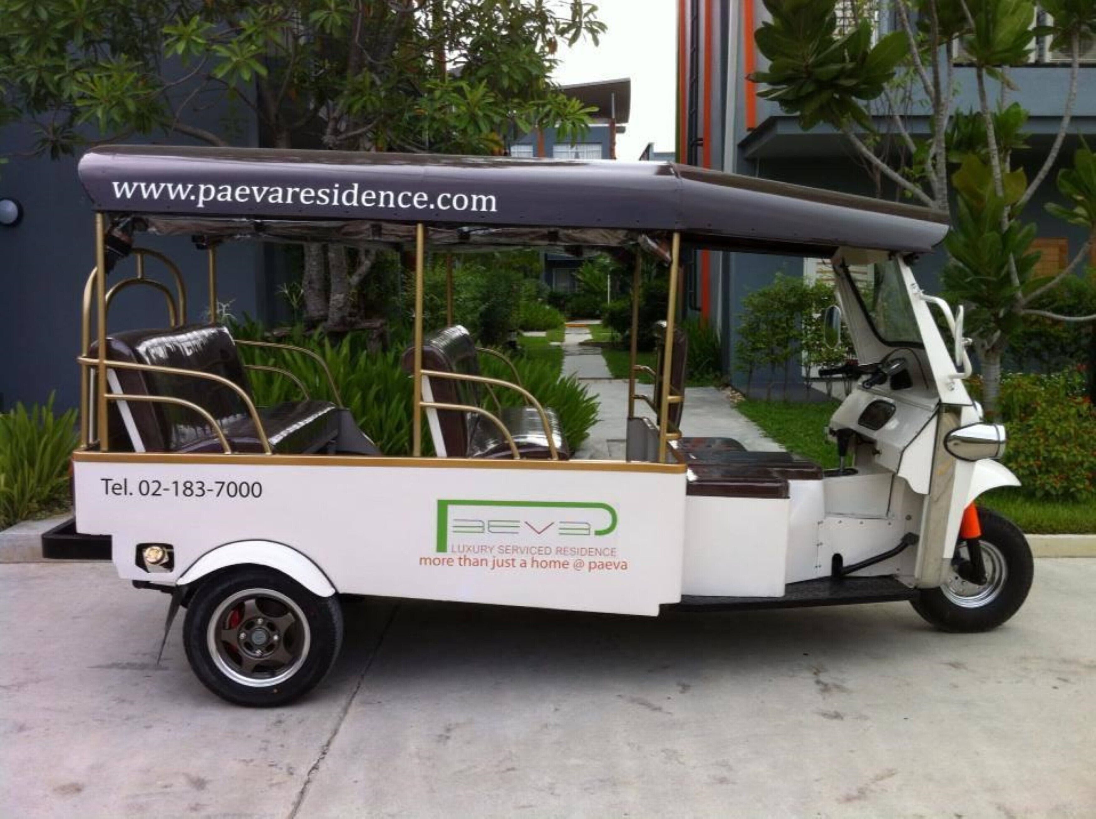 A three-wheeled vehicle with a canopy, branded with "BEV3" and "Luxury Serviced Residence." It has a contact number and a website URL displayed.