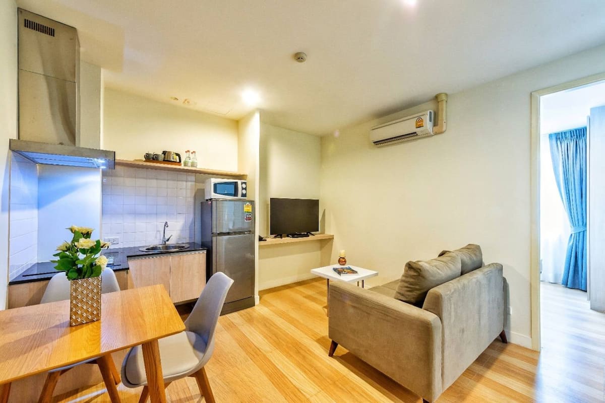 A compact living space with a kitchenette, a dining area, a sofa, and a television.