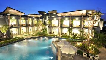 A hotel with a swimming pool, outdoor seating, and multiple balconies.