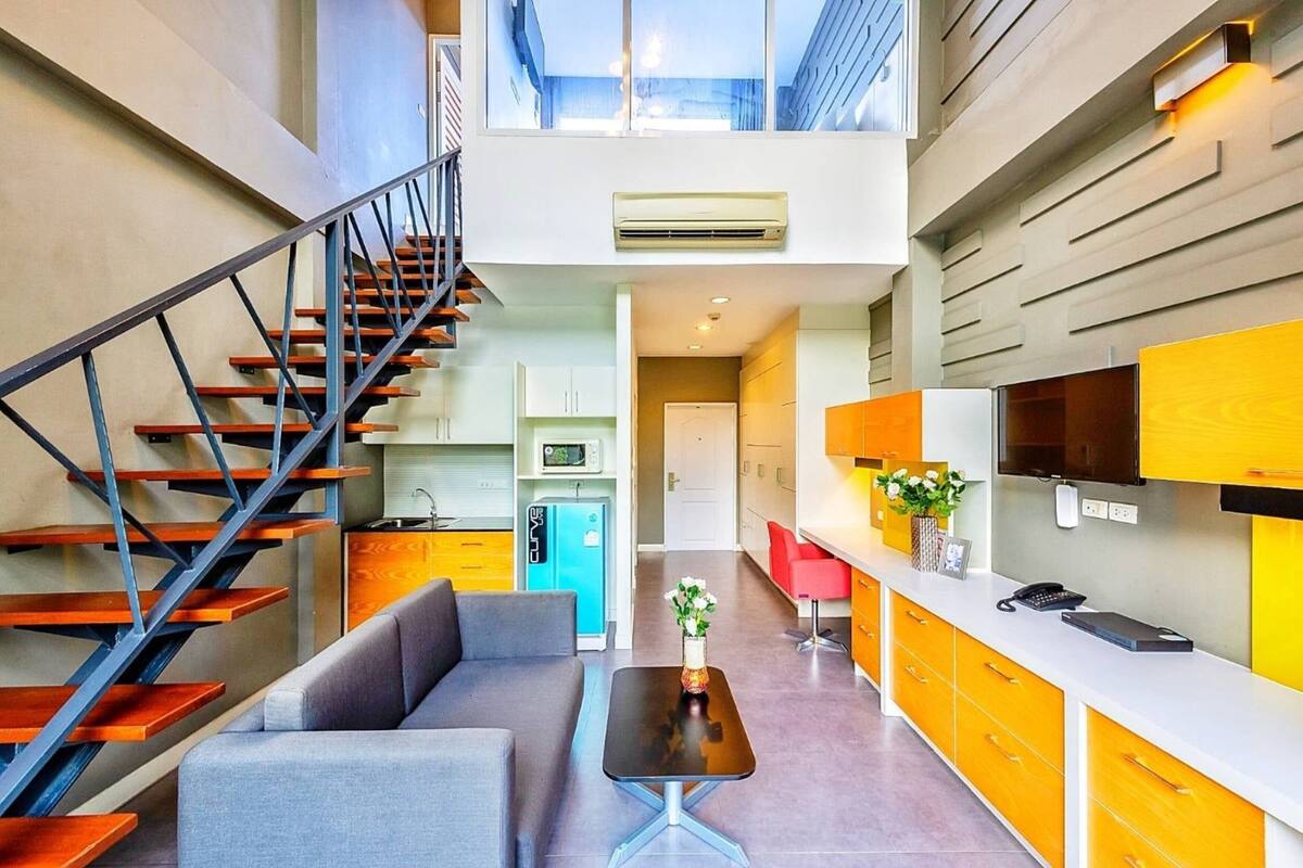 A modern interior with a staircase, a sofa, a table, and a kitchen area.