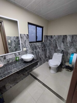Un baño con lavamanos blanco, inodoro y espejo.