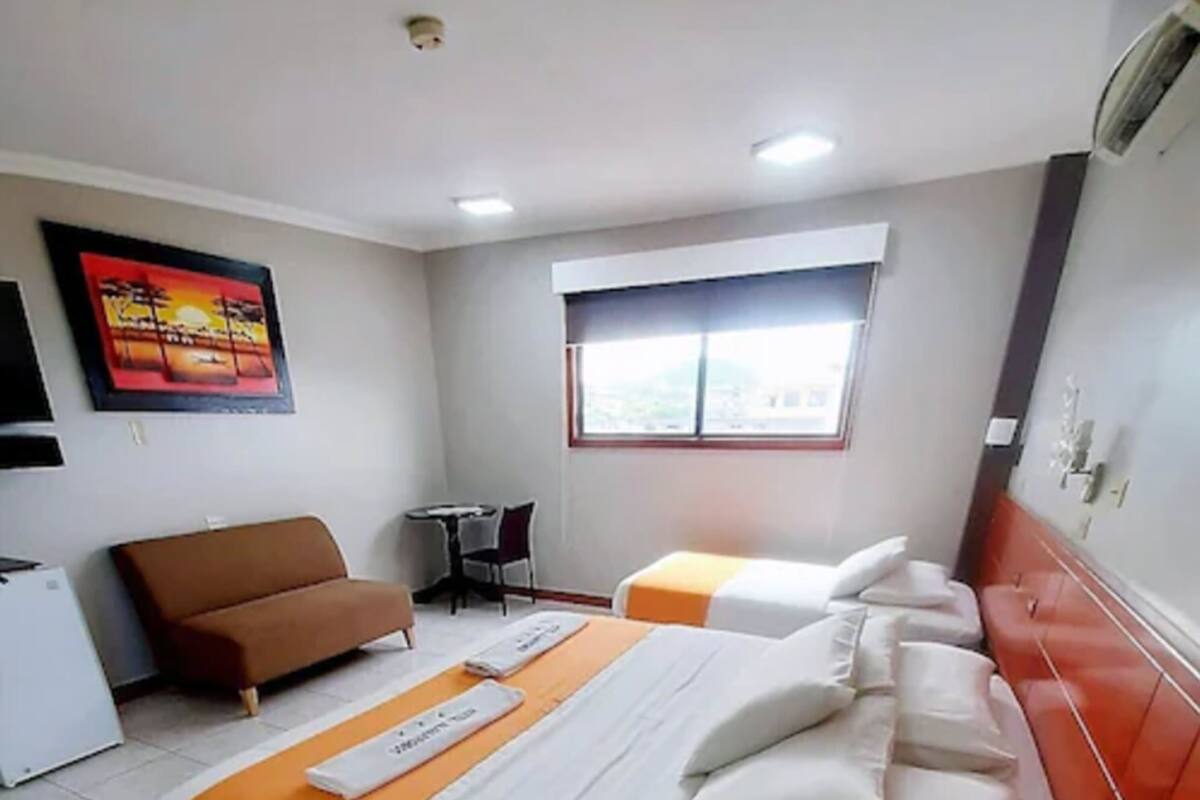 Una habitación de hotel con una cama, un sofá, una mesita y una ventana.
