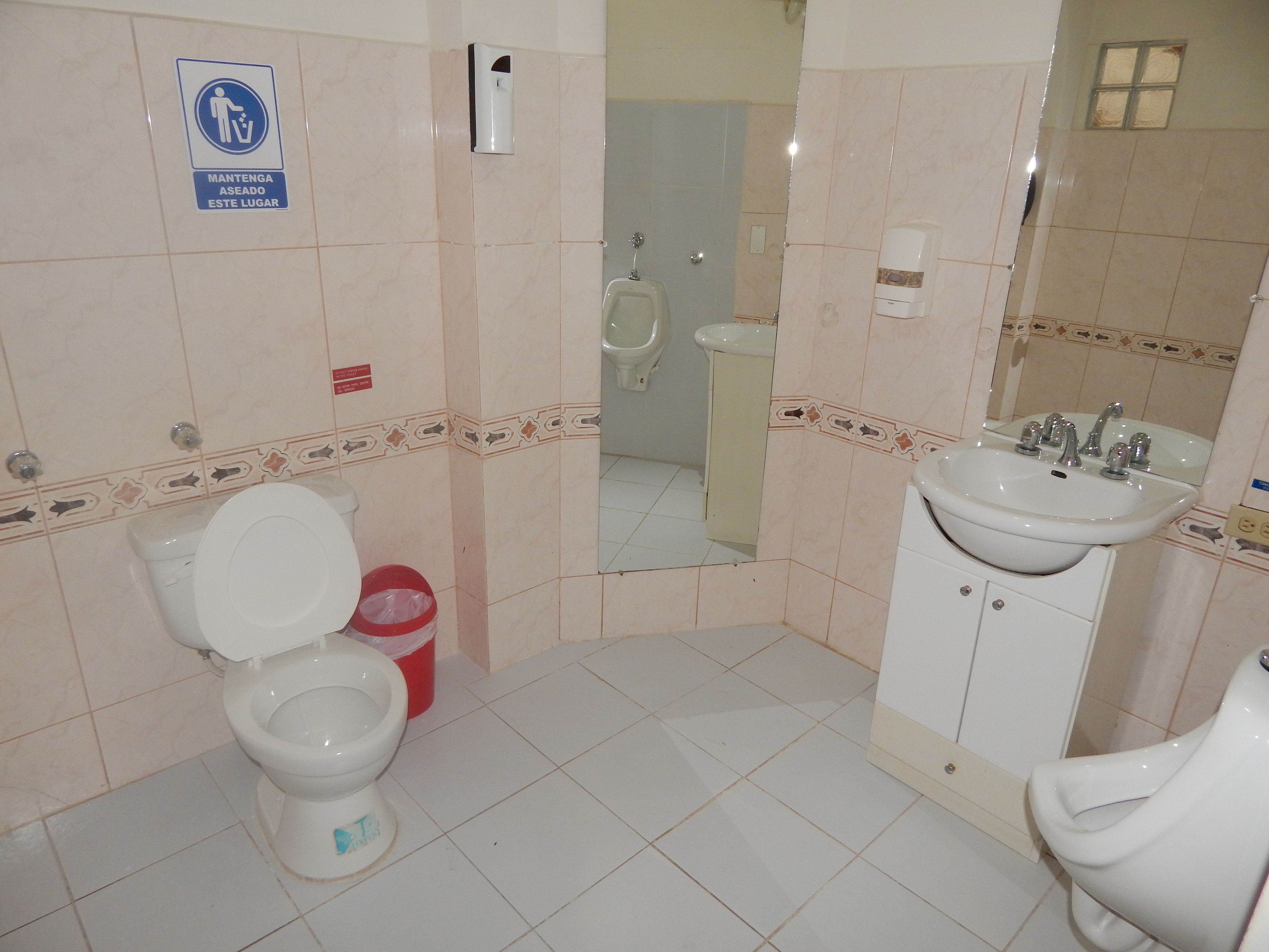 Ein Badezimmer mit Toilette, Bidet und Waschbecken. Dort steht ein Mülleimer und ein Handdesinfektionsmittelspender.