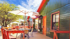 Une terrasse extérieure avec des tables et des chaises en bois, des parasols et une plateforme en bois.