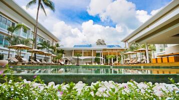 Una piscina al aire libre, sombrillas, sillones reclinables de piscina
