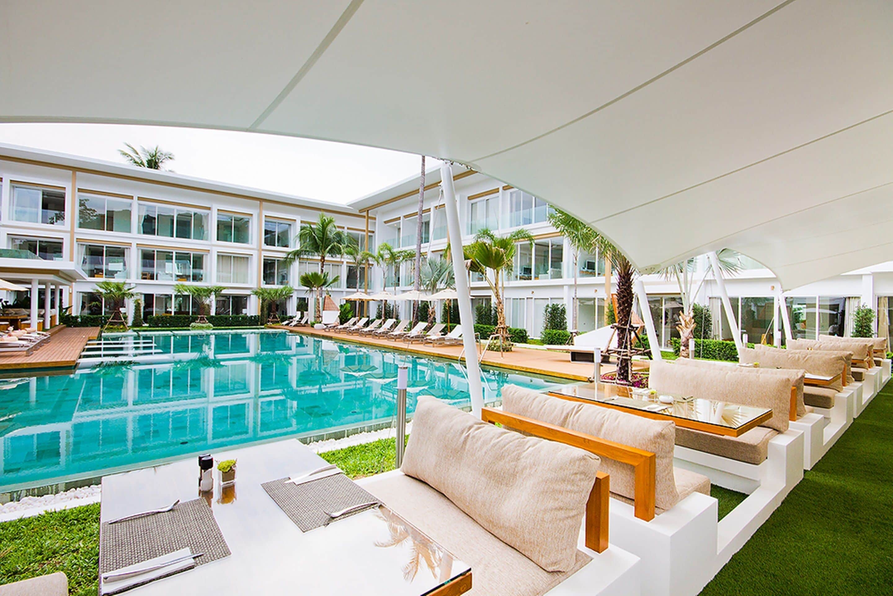 Un área junto a la piscina con sillones de descanso y una piscina grande.