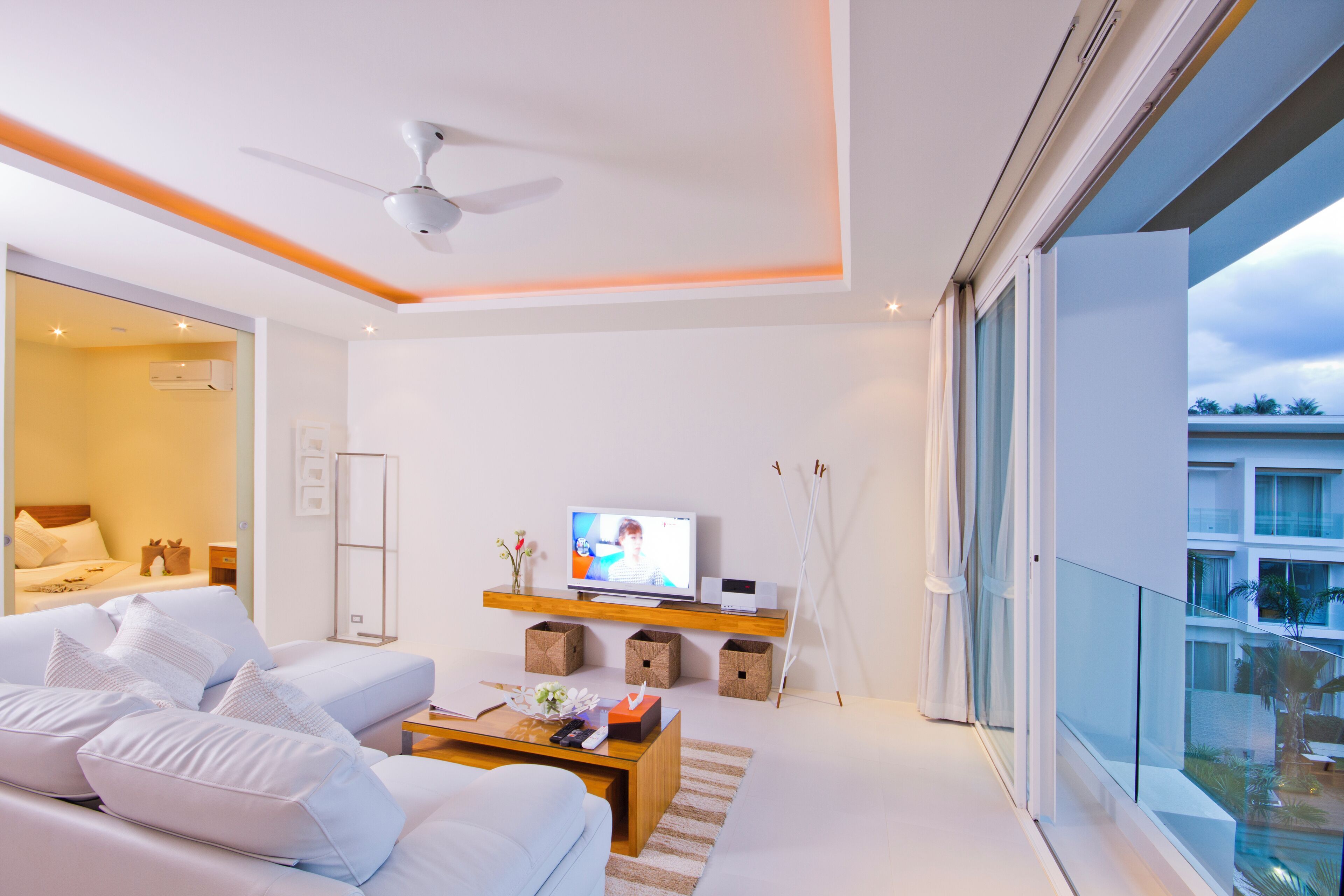 Een moderne woonkamer met een bank, salontafel, televisie en een balkon met uitzicht.