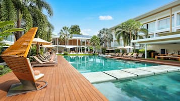 Una piscina al aire libre, sombrillas, sillones reclinables de piscina