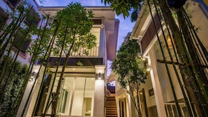 Un bâtiment moderne à deux étages, doté d’un escalier central, entouré de bambous et agrémenté d’une entrée bien éclairée.