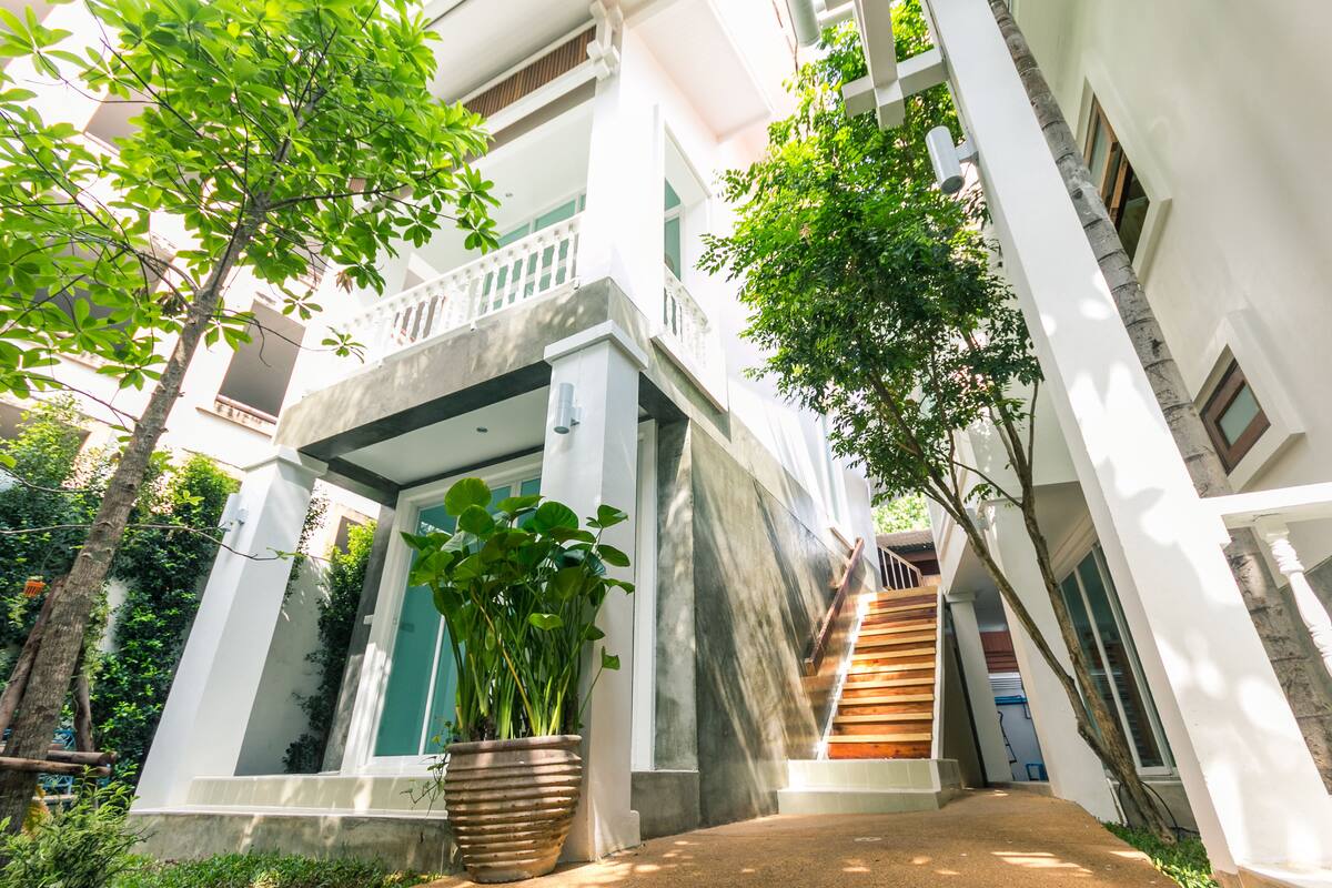 A multi-story building with a central staircase, potted plants, and a balcony.