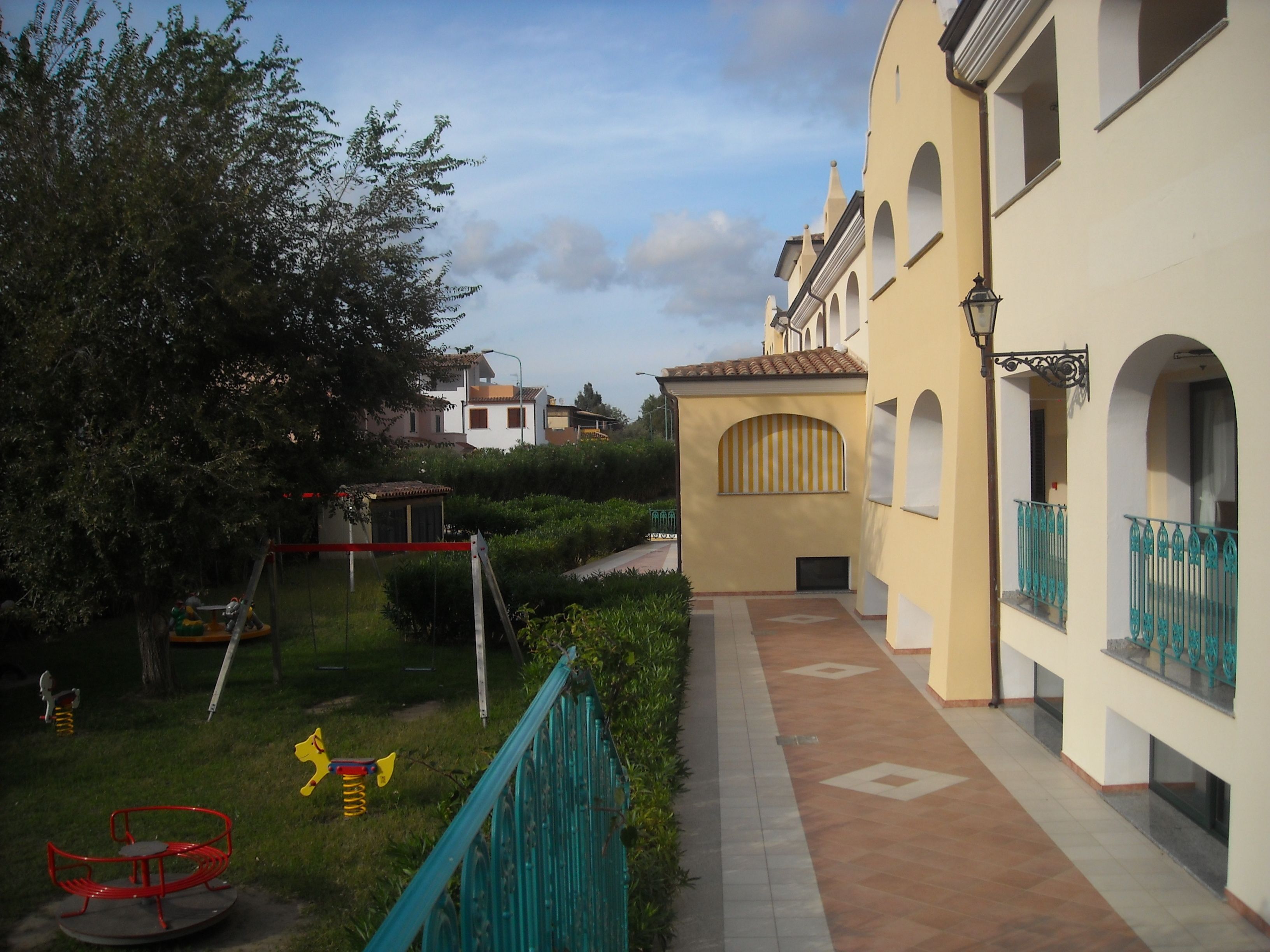 A courtyard with a playground, a pathway, and buildings with balconies.