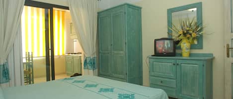 A bedroom with a bed, a wardrobe, a television, and a mirror.