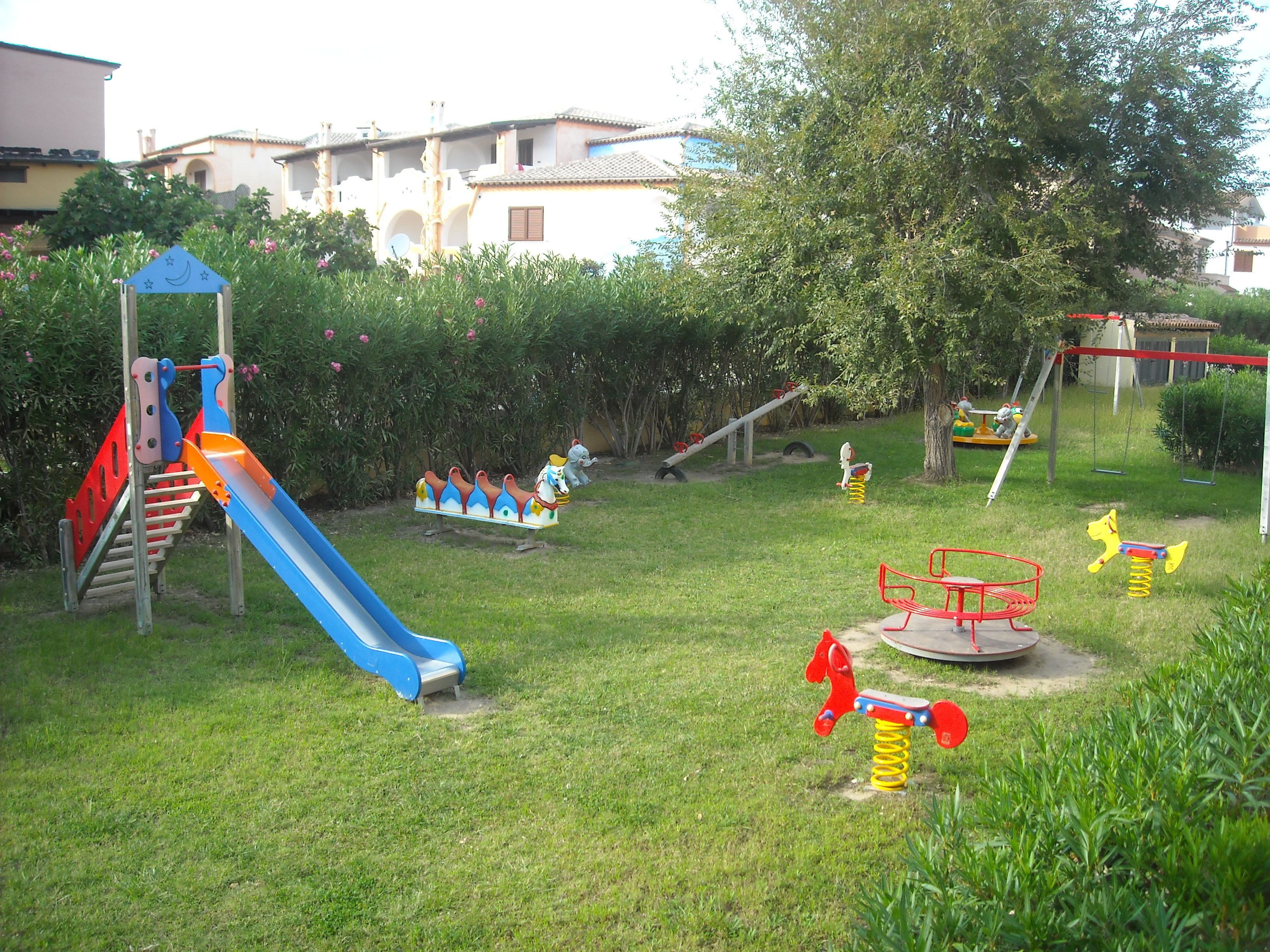 A playground with various play structures including a slide, swings, and a merry-go-round.