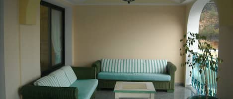 A cozy seating area with a sofa and a small table, a potted plant, and a view through an archway.