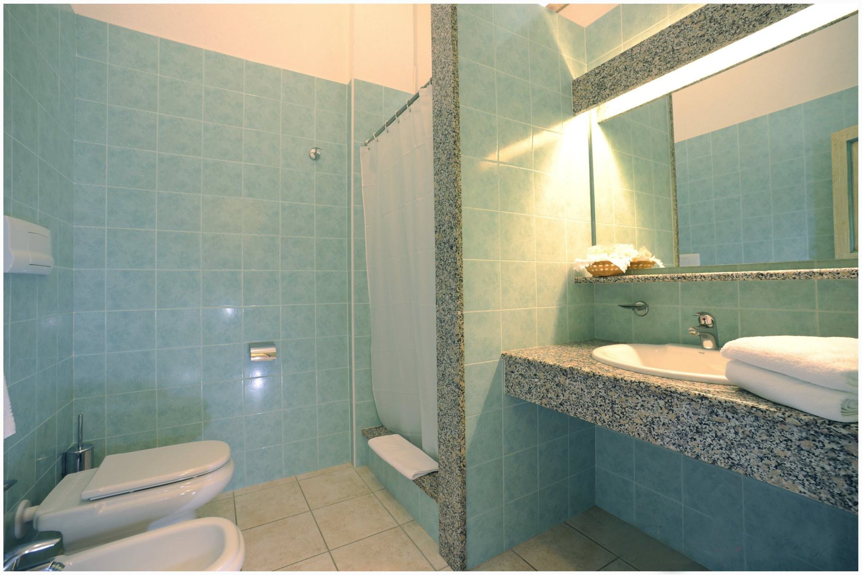 Ein Badezimmer mit Dusche, Toilette, Waschbecken und Spiegel.