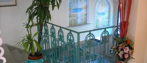 A staircase with ornate metal railings, a potted plant, and a vase with flowers.
