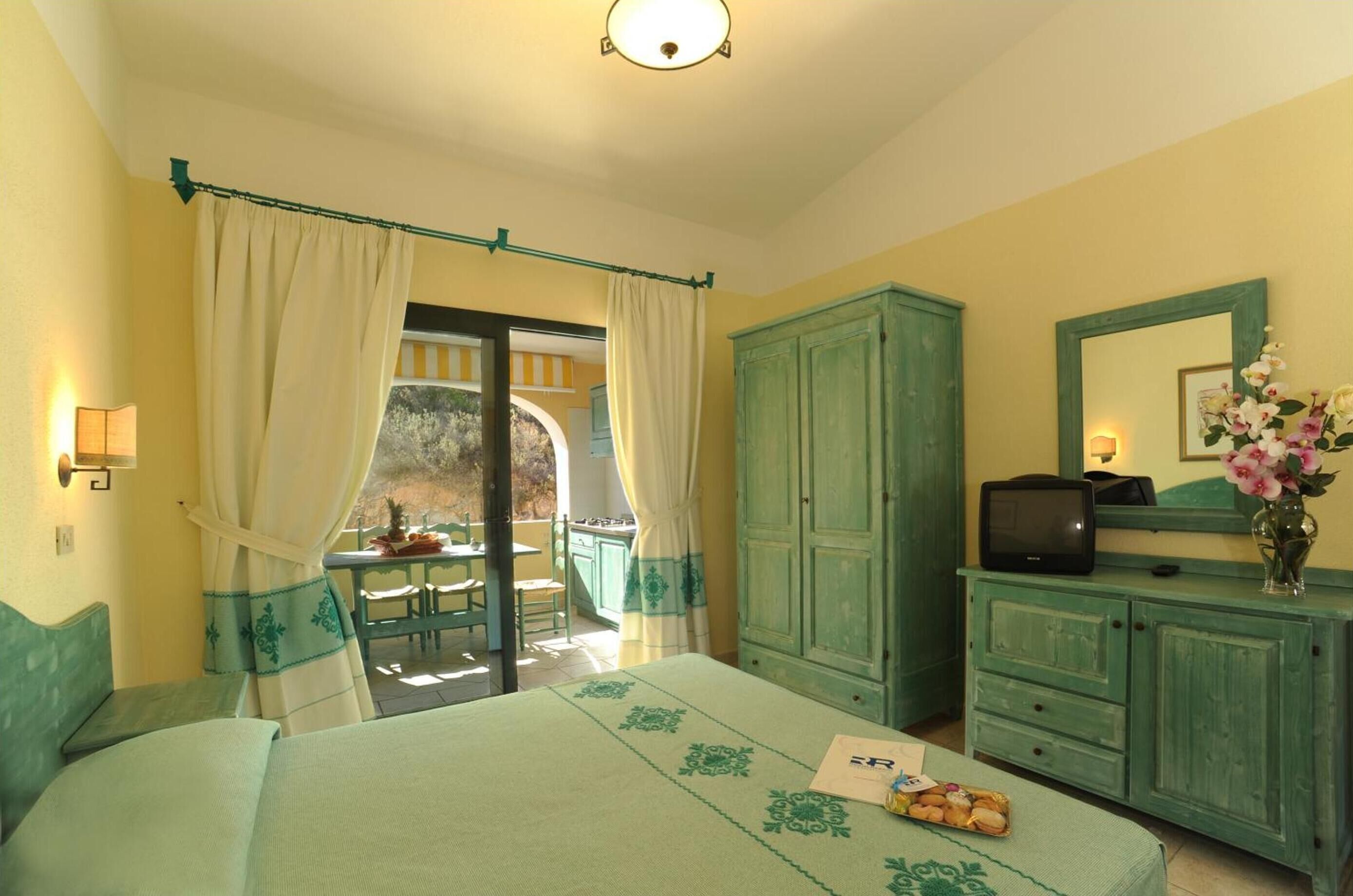 A bedroom with a bed, a desk, a television, and a cabinet.