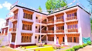 A multi-story building with balconies, a central courtyard, and outdoor seating. - TIH Hotel Kidar, Leh (Leh)